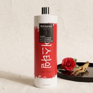 Bouteille de lissage coréen Bôheme Secret Paris d'un litre devant un fond de papier de riz, avec une fleur de camélia rouge et une racine de ginseng sur un plateau laqué